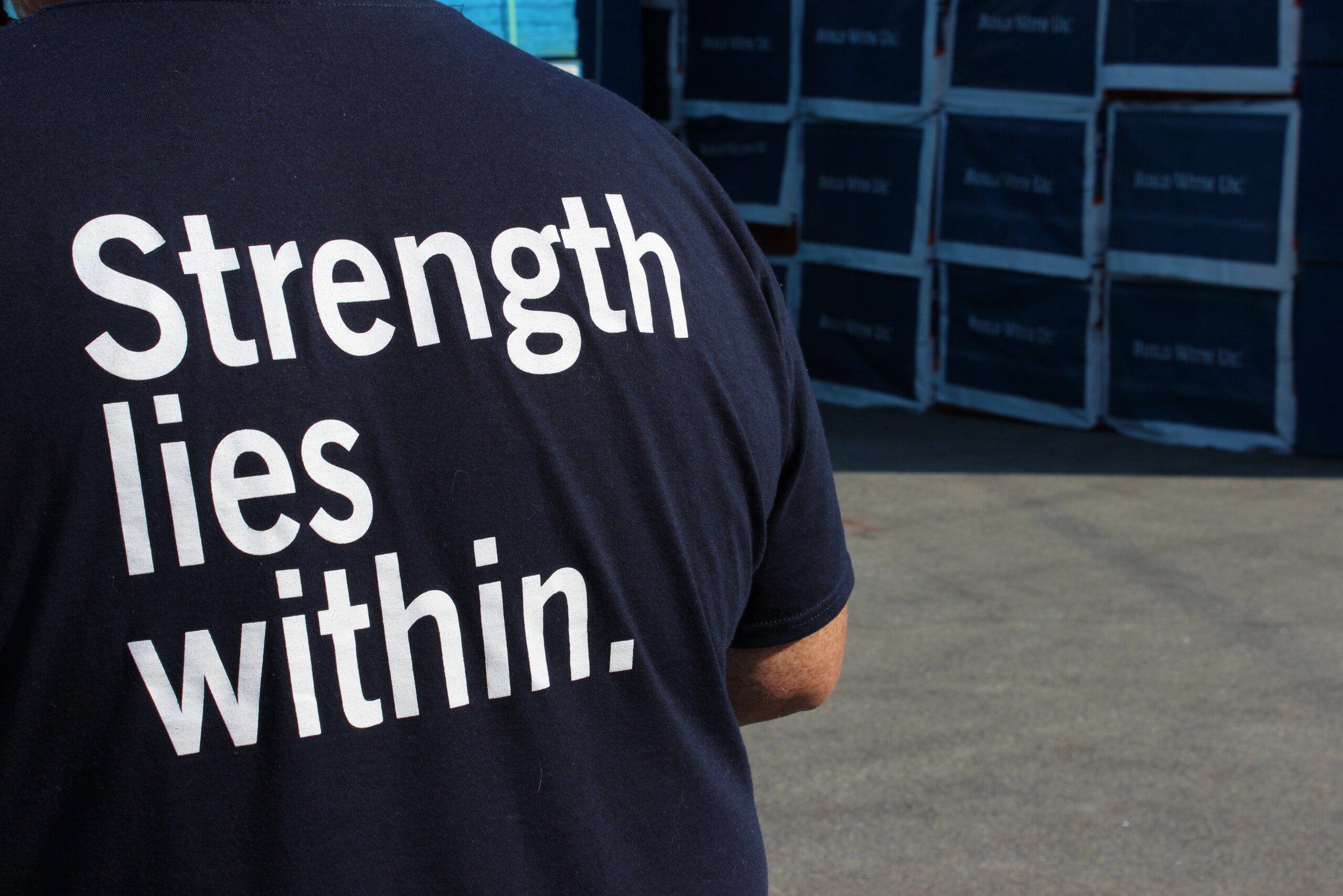 A person wearing a blue shirt with “Strength lies within.” written on the back is facing away from the camera.