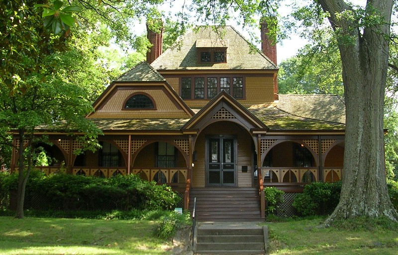 A Victorian style home known as the Wren’s Nest, which features details typical of the style, like shingle work, gabled windows and an asymmetrical facade. The home is primarily yellow with brown trim and red brick details. 