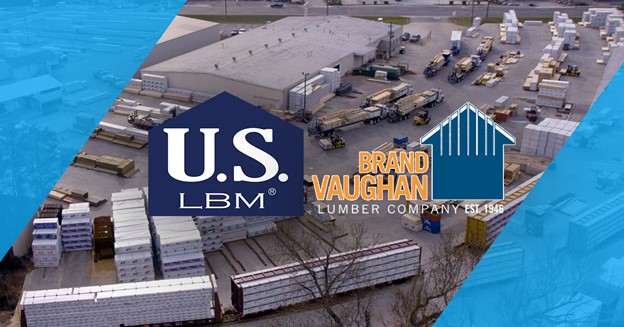 A picture of a warehouse has two logos on it. The US LBM logo is on the left, and the Brand Vaughan Lumber logo is on the right.