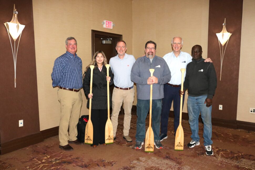 The Row the Boat Award winners are posing with their paddles, smiling for the camera.