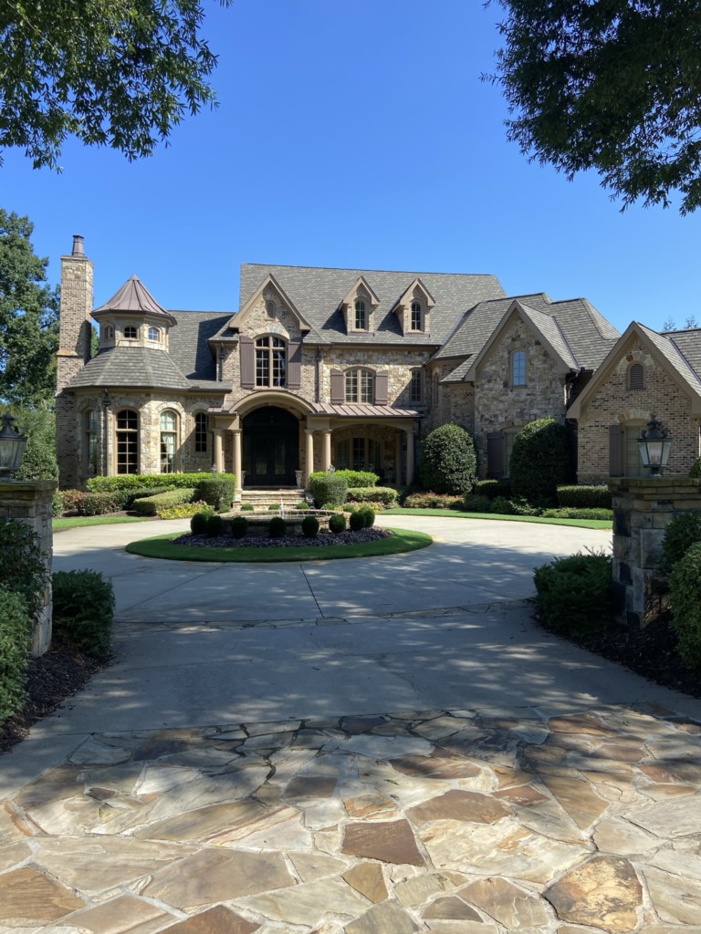 A custom two-story home in Atlanta with a stone exterior and a classic finish. There is a circular driveway with stone pavement.