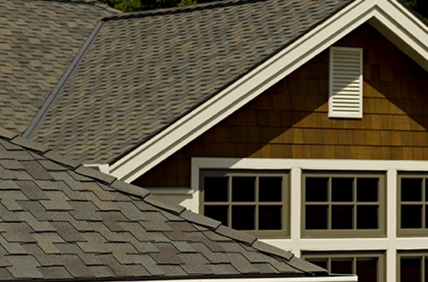 A cedar-shake house with gray roofing shingles and white trim is pictured.