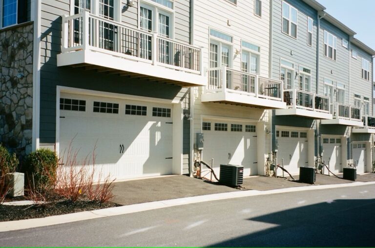 Townhomes with white and gray siding and stone exteriors are pictured. They have single-car garages attached.