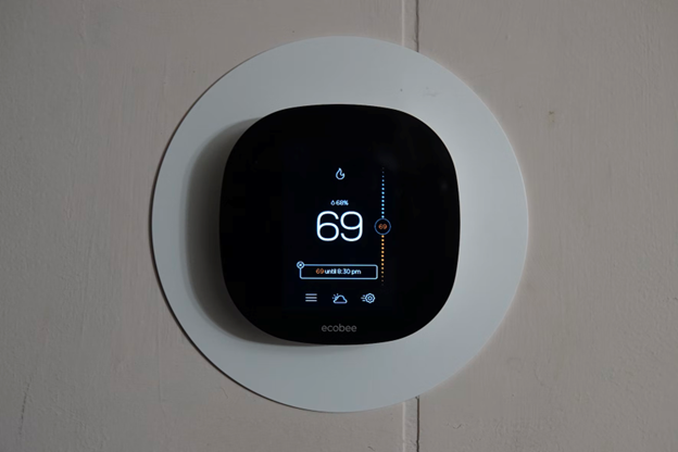 A white smart home thermostat from ecobee is mounted to a wall.