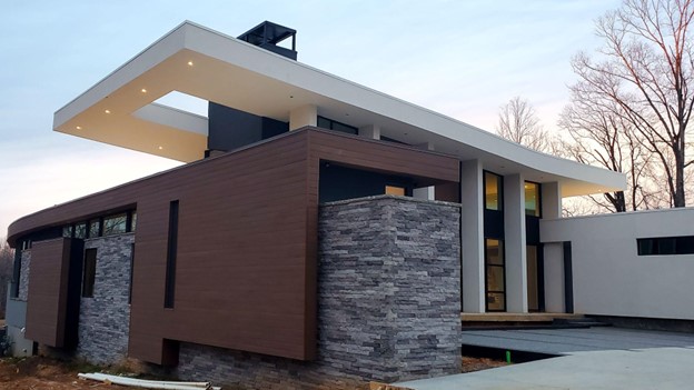 View of the exterior of a modern home. The exterior has wood siding and stone accents.