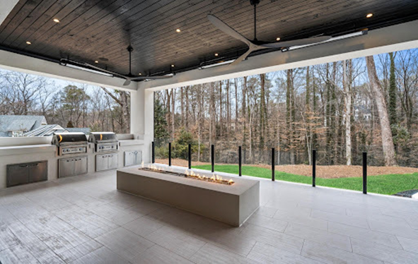 An outdoor entertainment and kitchen area that features outdoor grills and a rectangular firepit.