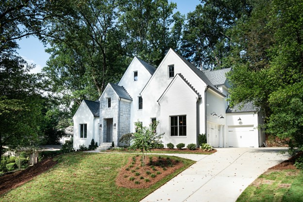 The front exterior of a white three-story home with a paved driveway.