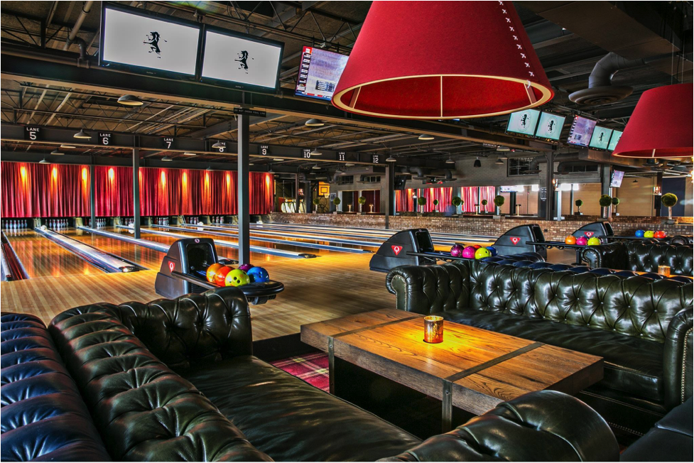 Image of a bowling alley with large sectional couches and bright lights.